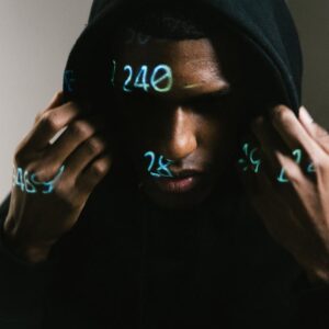 Person in black hoodie with digital numbers projected, creating a cybernetic ambiance.
